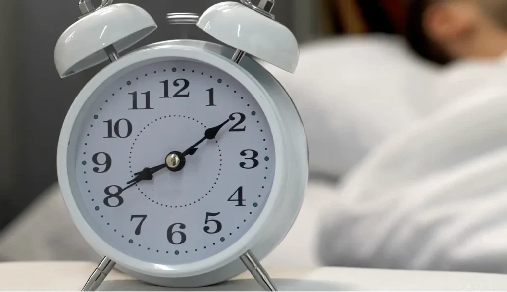 Sveglia analogica appoggiata sul letto che segna le sette del mattino