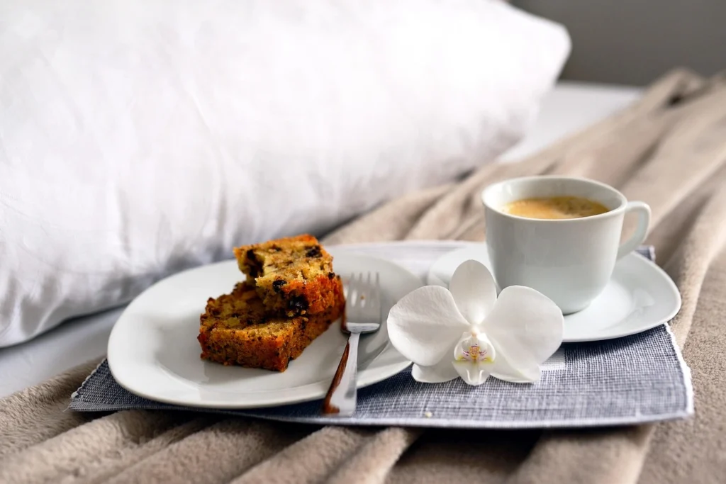 Vassoio con una fetta di dolce e una tazza di caffè appoggiato sul letto